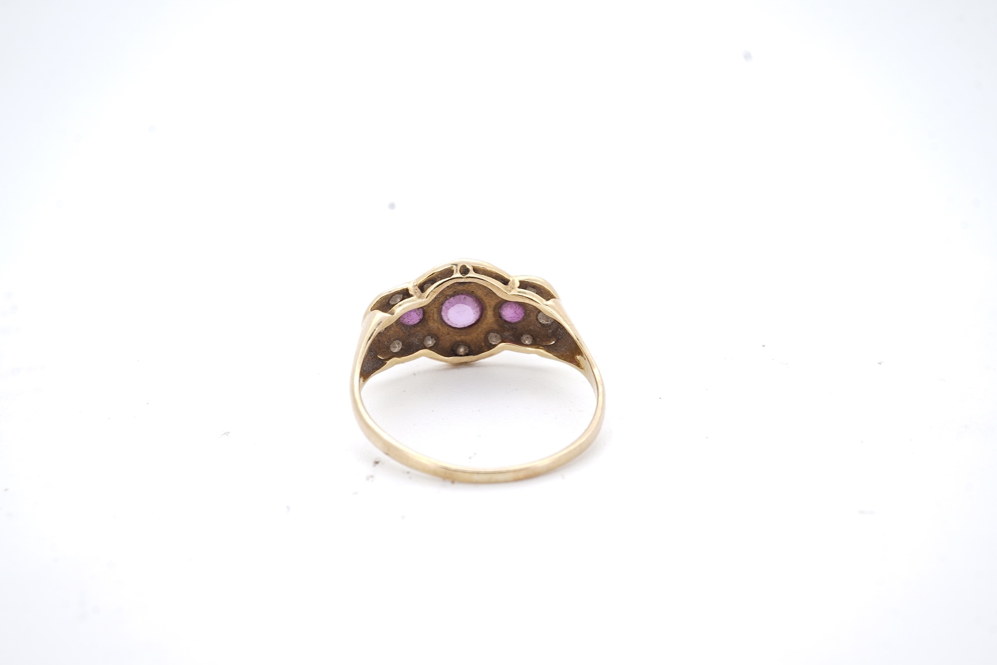 A modern 18ct gold, ruby and diamond cluster ring, the three rubies bordered by small round brilliants, size O, gross weight 2.3 grams.